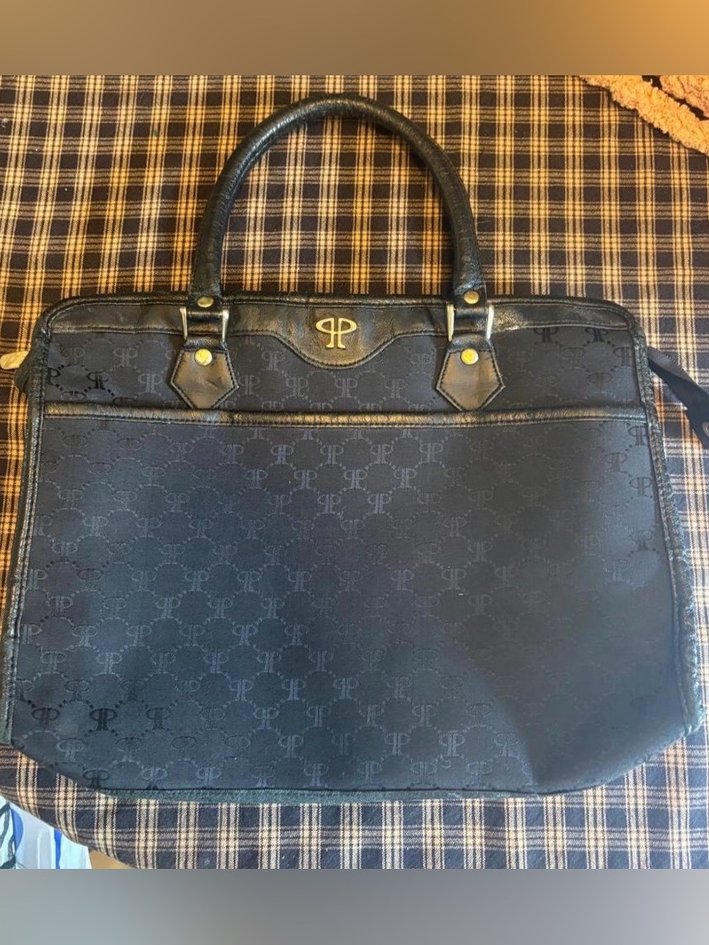 Black leather handbag with repeating monogram pattern and gold accents